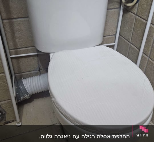 אסלה עם חיבורי צנרת בחדר אמבטיה